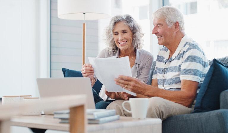 Das Erbe braucht einen sicheren Platz. Ein älteres Ehepaar, das zu Hause auf dem Sofa Papierkram erledigt