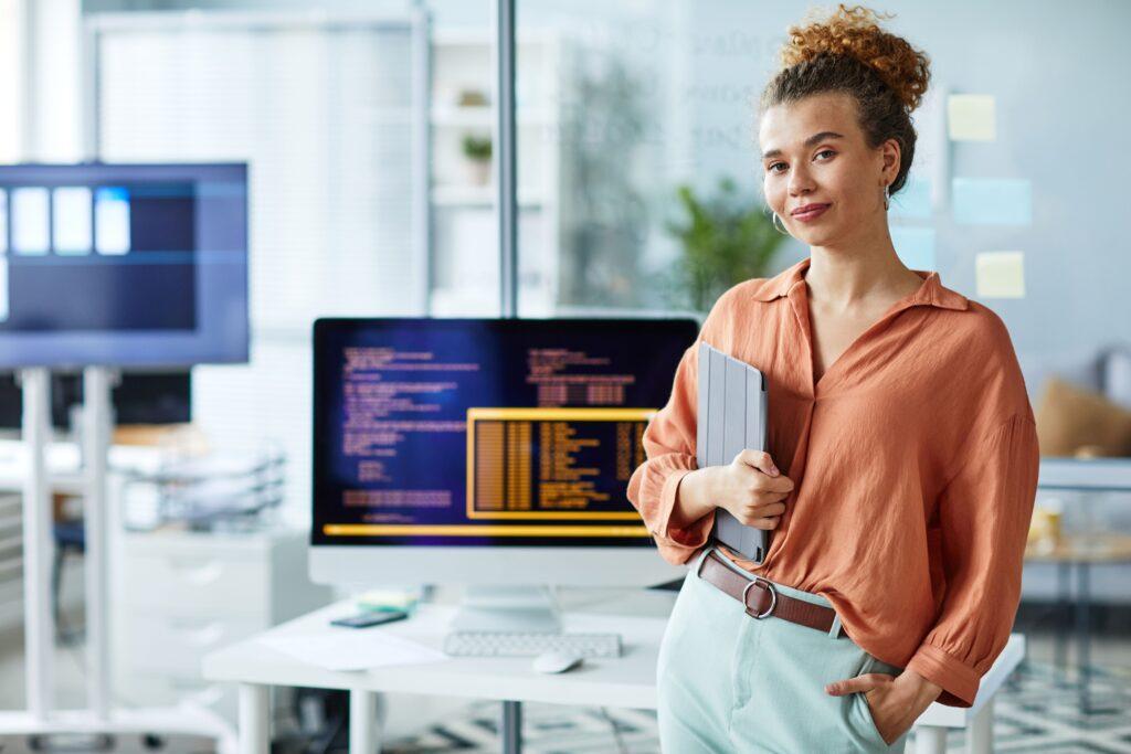 Eine Frau steht vor einem Tisch auf dem ein Computer steht