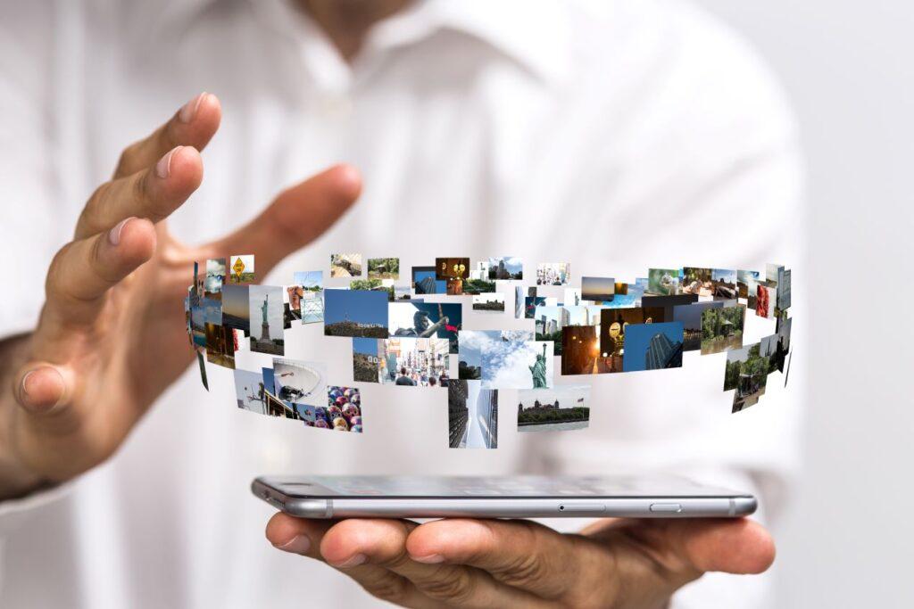 Schwebende digitale Fotos über einem Smartphone, Symbol für die Umwandlung von Dias und Fotos in digitale Dateien zur modernen Archivierung.