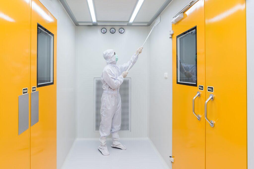 Fachkraft in vollständiger Schutzkleidung beim Reinraum reinigen in einem modernen, ISO-konformen Umfeld